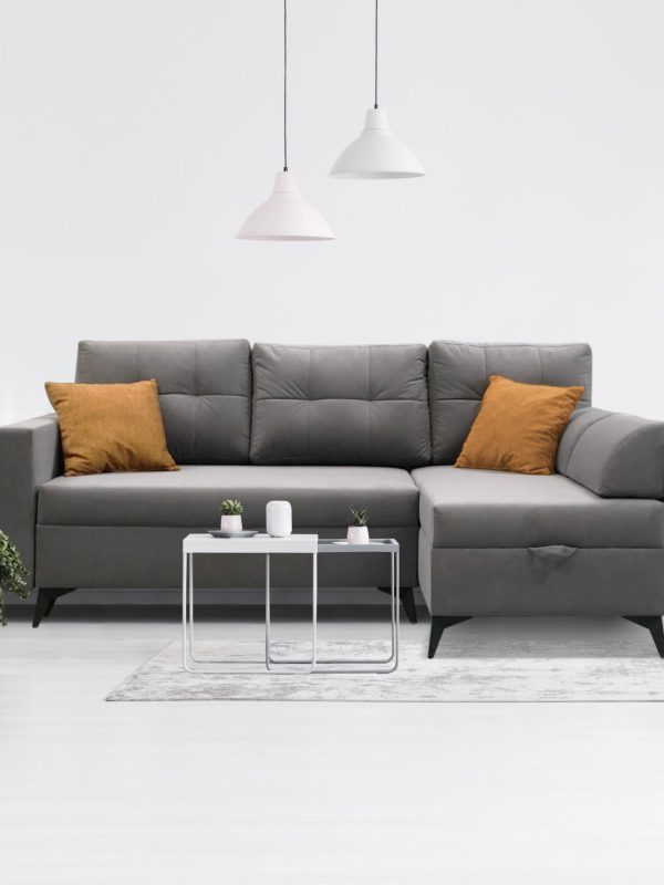 Patterned wooden armchair in white living room interior with pink pillows on grey sofa. Real photo